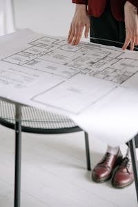 Person examining a detailed architectural floor plan on a table indoors with a focus on design.